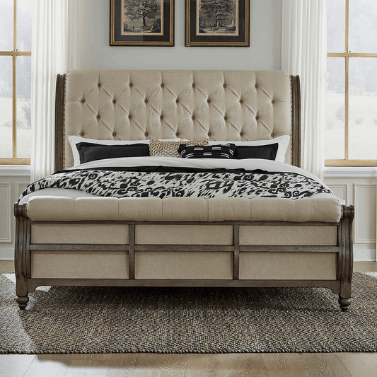 Americana Farmhouse queen sleigh bed with tufted upholstered headboard and footboard in a wire brushed dusty taupe finish.